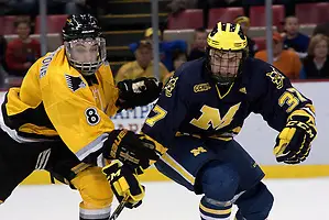 Photo By: Erica Treais Michigan's Mac Bennett and Michigan Tech's Jacob Johnston fight for the puck. (Erica Treais)