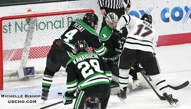 Photo By: Michelle Bishop Nebraska-Omaha's Taylor Ward (17) sends the puck past North Dakota goalie Adam Scheel during the third period. Nebraska-Omaha beat North Dakota 4-3 Saturday night at Baxter Arena. (Photo by Michelle Bishop) (Michelle Bishop)