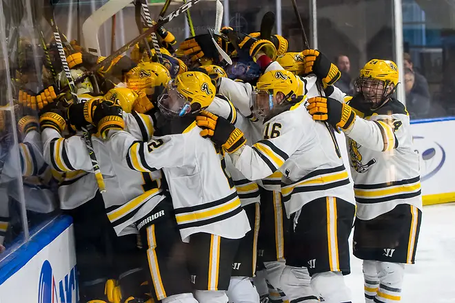 Photo By: 2019 Omar Phillips AIC players celebrate an overtime win over Robert Morris in the Atlantic Hockey semifinals (2019 Omar Phillips)